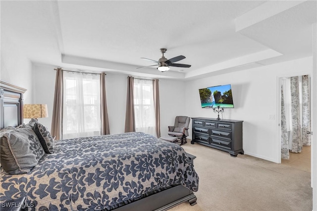 carpeted bedroom with a tray ceiling and ceiling fan