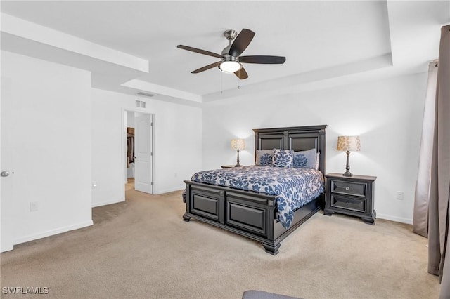 carpeted bedroom with a raised ceiling and ceiling fan