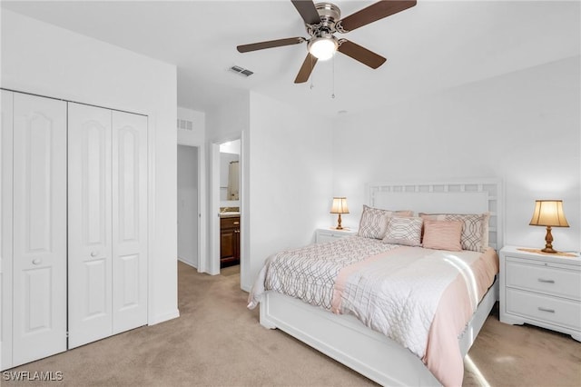 carpeted bedroom with ceiling fan, a closet, and ensuite bathroom