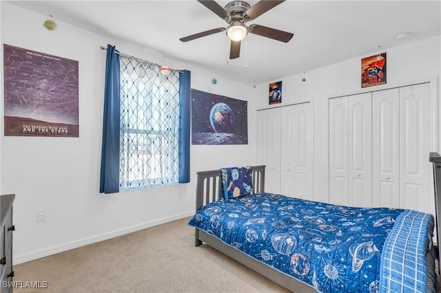 carpeted bedroom with ceiling fan and two closets