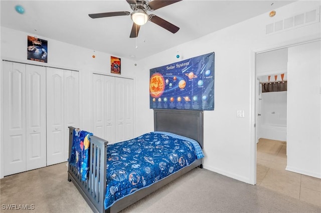 bedroom with ceiling fan and two closets