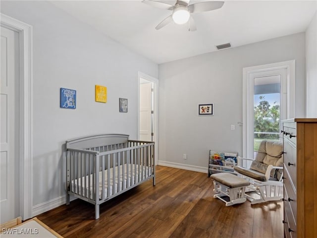 bedroom featuring ceiling fan, a nursery area, and dark hardwood / wood-style flooring