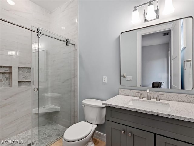 bathroom with toilet, a shower with door, and vanity