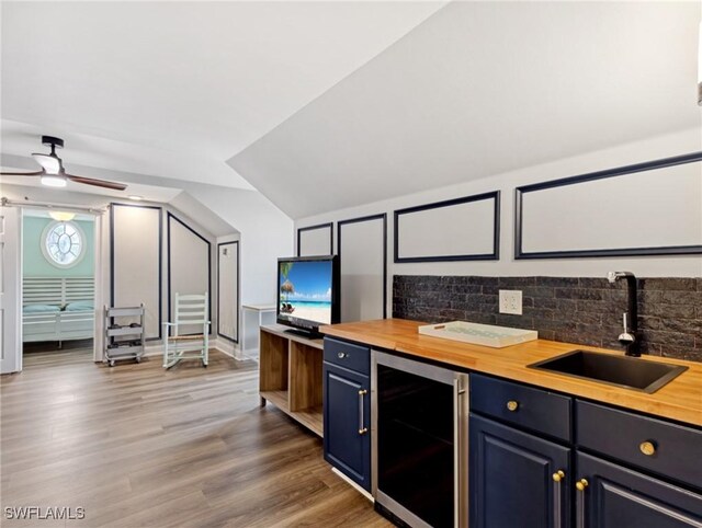 kitchen with wine cooler, hardwood / wood-style flooring, wooden counters, and sink