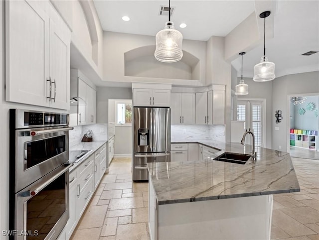 kitchen with white cabinetry, stainless steel appliances, decorative backsplash, decorative light fixtures, and sink