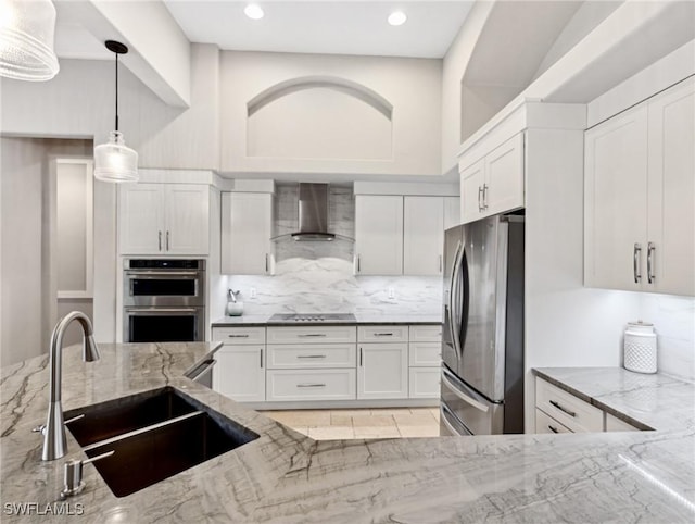 kitchen featuring light stone counters, white cabinetry, stainless steel appliances, and wall chimney exhaust hood