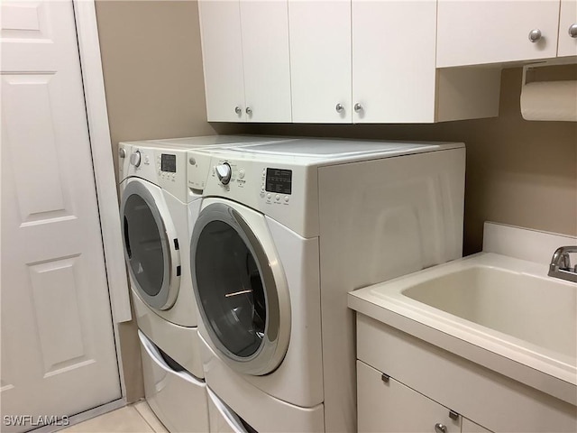 washroom with cabinets, light tile patterned floors, washer and clothes dryer, and sink