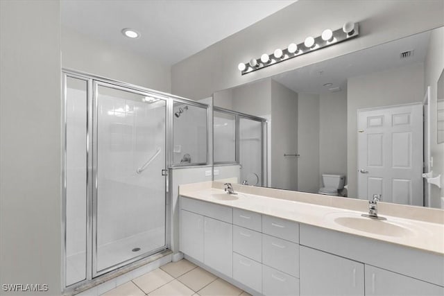 bathroom with tile patterned flooring, vanity, toilet, and a shower with shower door