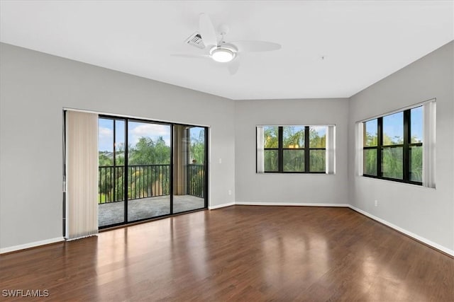 spare room with dark wood-type flooring, ceiling fan, and a healthy amount of sunlight