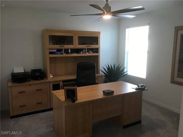 home office featuring ceiling fan, baseboards, and light colored carpet