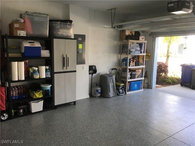 garage with concrete block wall, electric panel, and a garage door opener