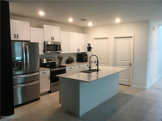 kitchen with white cabinetry, sink, stainless steel appliances, and a center island with sink