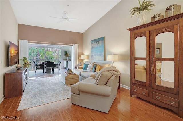 living room with ceiling fan, light hardwood / wood-style flooring, and vaulted ceiling