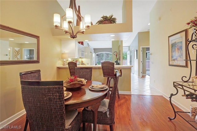 dining room featuring light wood-type flooring, an inviting chandelier, and a high ceiling