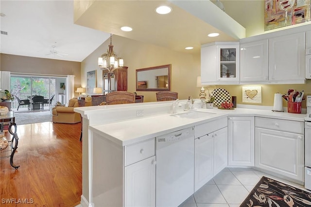 kitchen featuring white cabinetry, lofted ceiling, kitchen peninsula, and white appliances