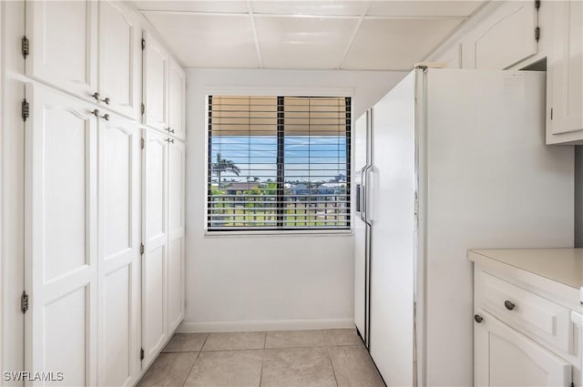 kitchen featuring white cabinetry, white refrigerator with ice dispenser, and light tile patterned flooring