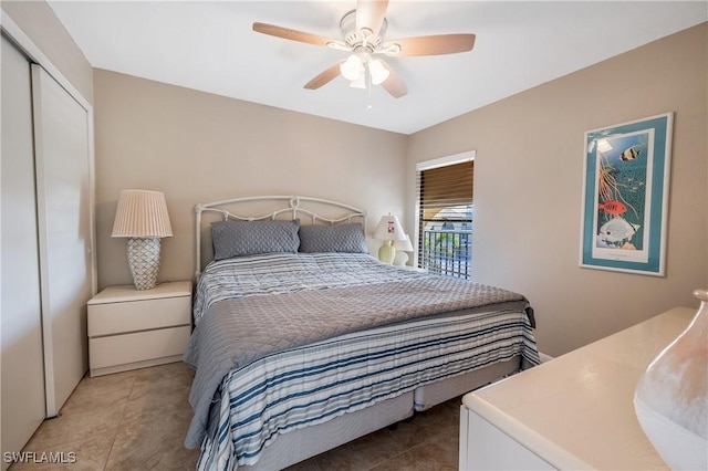 bedroom featuring ceiling fan, dark tile patterned flooring, and a closet