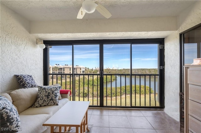 sunroom with ceiling fan and a water view