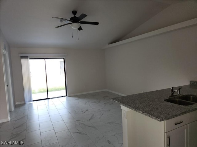 unfurnished living room featuring ceiling fan, sink, and vaulted ceiling