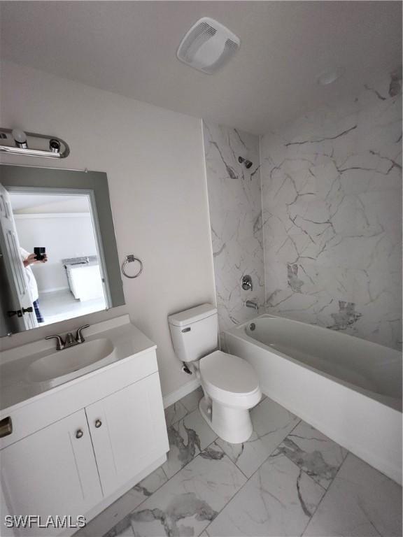 full bathroom featuring vanity, tiled shower / bath combo, and toilet