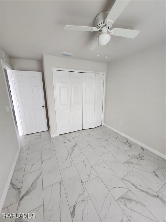 unfurnished bedroom featuring ceiling fan and a closet