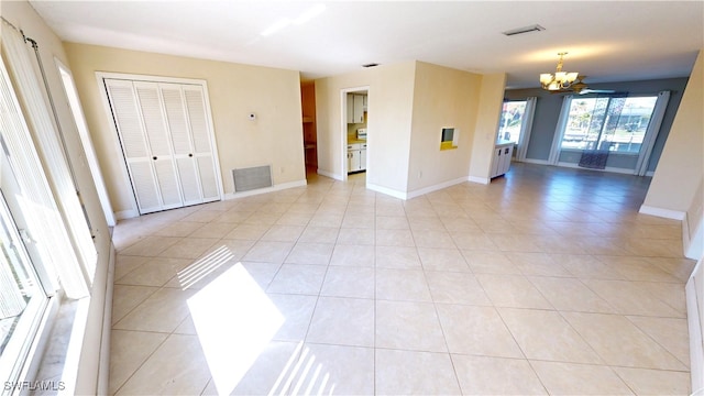 empty room with light tile patterned floors and a notable chandelier