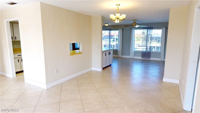 tiled spare room with ceiling fan with notable chandelier