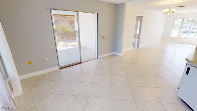 empty room with light tile patterned floors and a chandelier