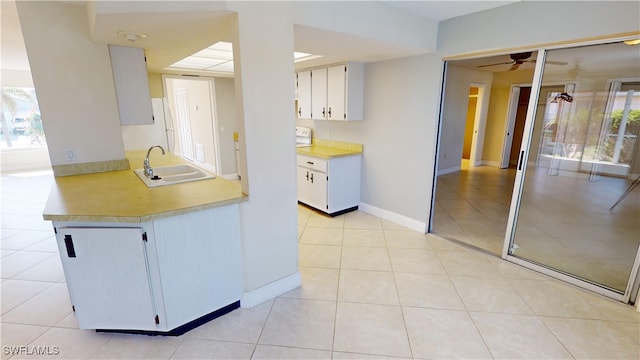 kitchen with white cabinets, light tile patterned flooring, ceiling fan, and sink