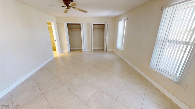 unfurnished bedroom with multiple closets, ceiling fan, and light tile patterned flooring