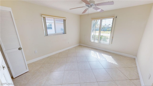 tiled empty room featuring ceiling fan