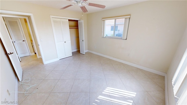 unfurnished bedroom featuring ceiling fan, light tile patterned flooring, and a closet