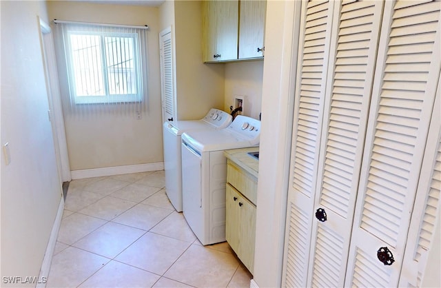 washroom with cabinets, light tile patterned floors, and washing machine and clothes dryer