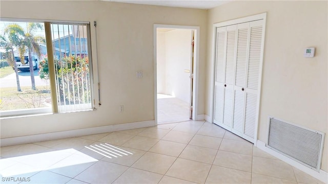 unfurnished bedroom featuring light tile patterned floors, a closet, and multiple windows