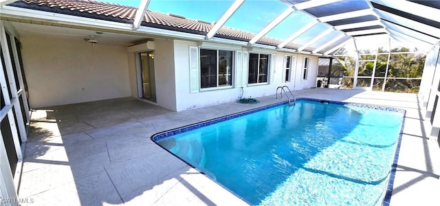 view of pool with glass enclosure and a patio