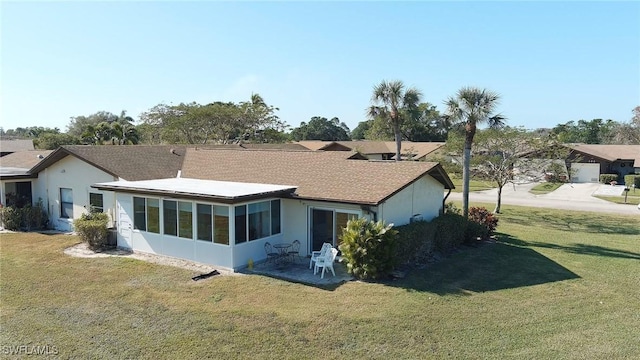 back of house featuring a lawn, a sunroom, and a patio