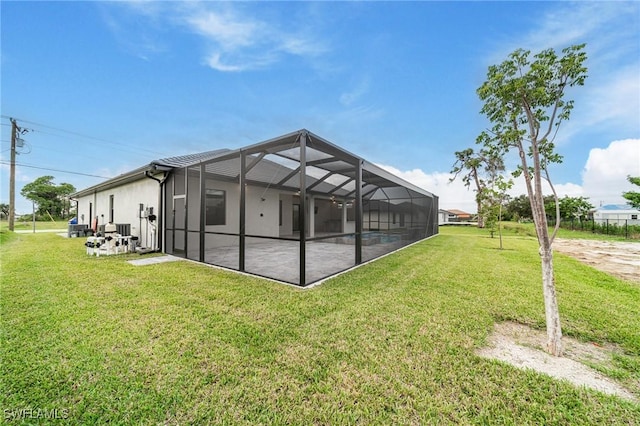 back of property with a lawn, a patio area, and a lanai