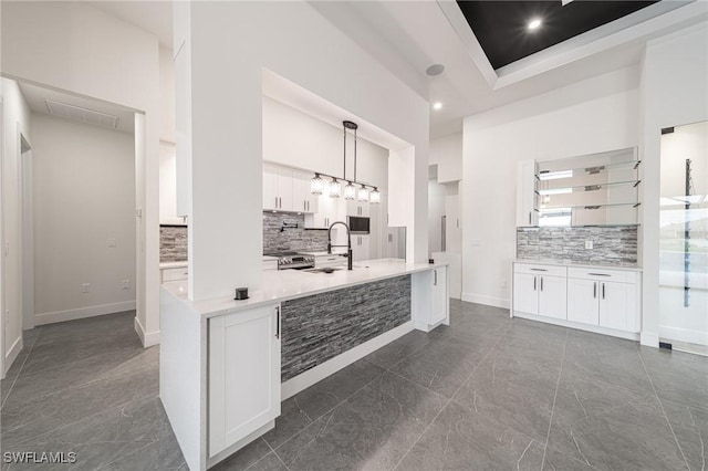 kitchen featuring a raised ceiling, sink, pendant lighting, white cabinets, and a high ceiling