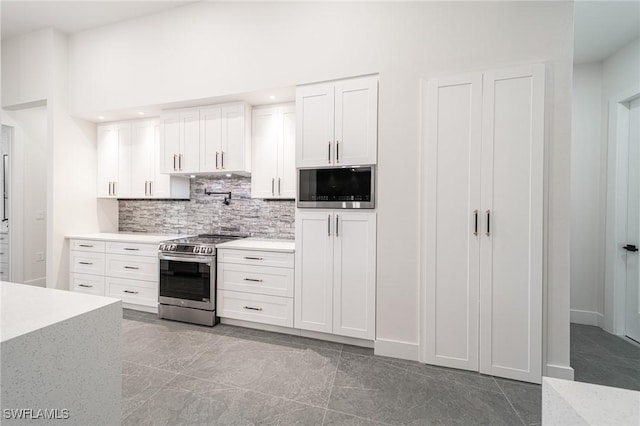 kitchen featuring built in microwave, white cabinetry, light tile patterned floors, backsplash, and stainless steel stove