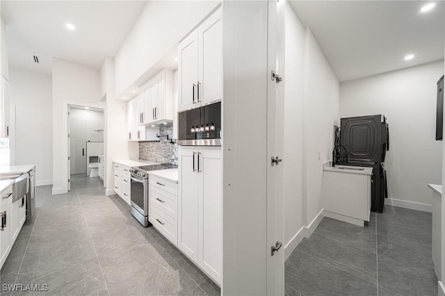 kitchen with backsplash, white cabinetry, and stainless steel electric range