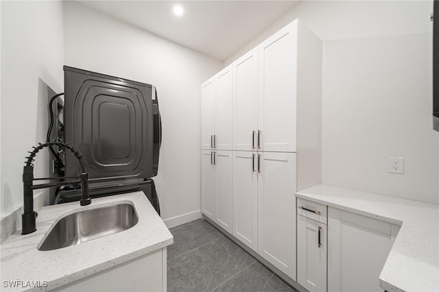 laundry room featuring cabinets, dark tile patterned floors, and sink