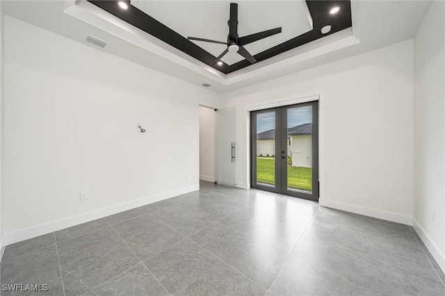 spare room featuring a tray ceiling, ceiling fan, and french doors