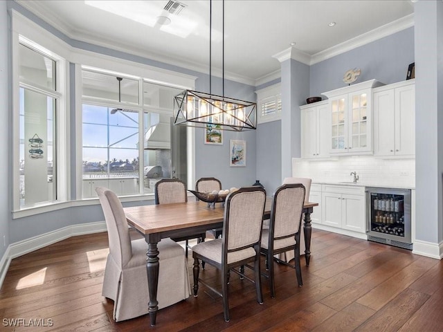 dining area featuring wine cooler, sink, crown molding, and dark hardwood / wood-style floors