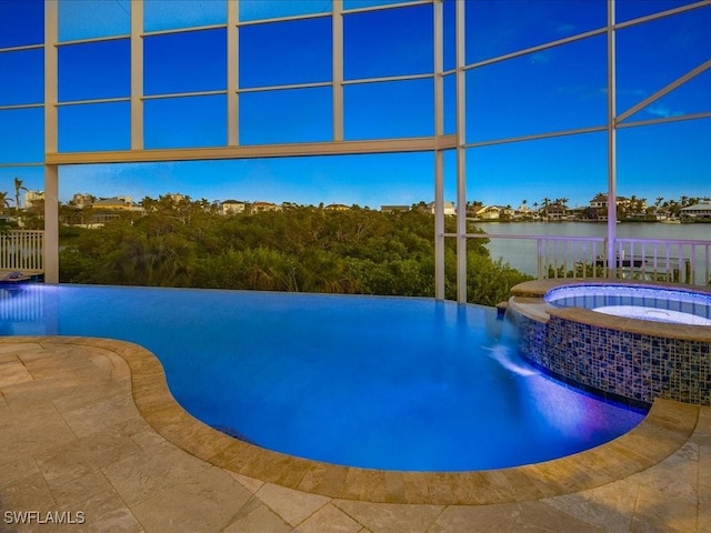 view of pool with an in ground hot tub, a water view, and a patio area