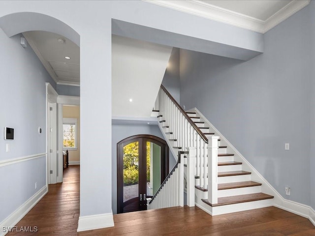 staircase featuring a high ceiling, ornamental molding, hardwood / wood-style floors, and french doors