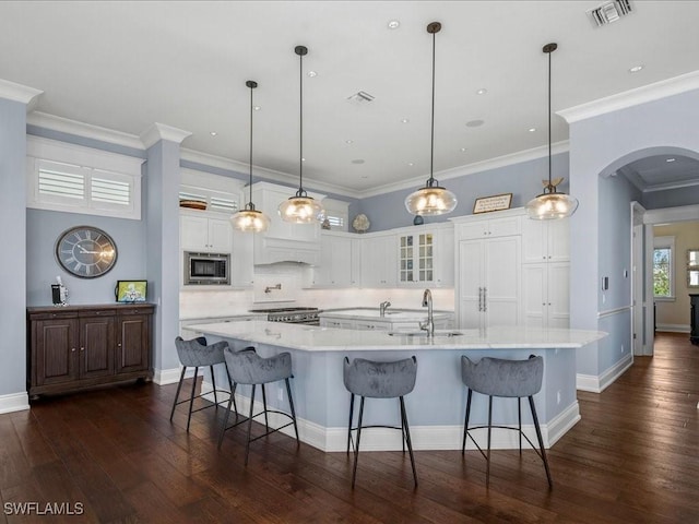 kitchen with hanging light fixtures, stainless steel microwave, and a spacious island