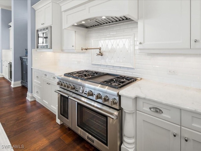 kitchen with custom exhaust hood, light stone counters, dark hardwood / wood-style floors, stainless steel appliances, and white cabinets