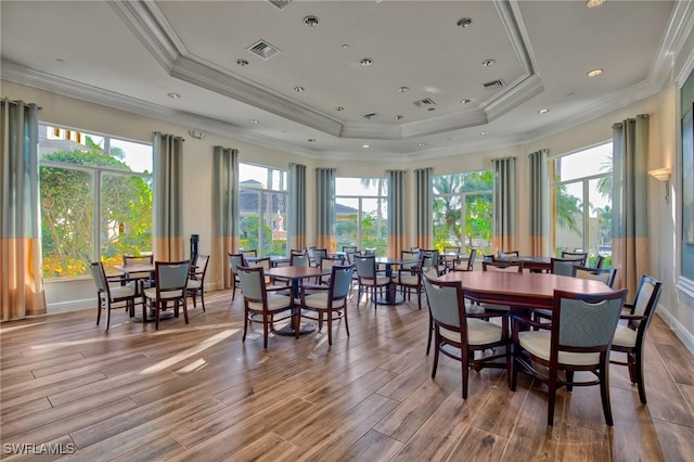 dining room with crown molding, light hardwood / wood-style flooring, and a raised ceiling