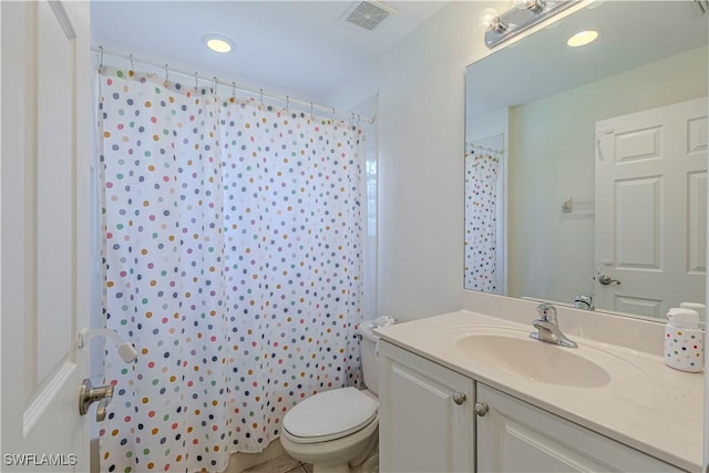 bathroom featuring tile patterned flooring, toilet, vanity, and walk in shower