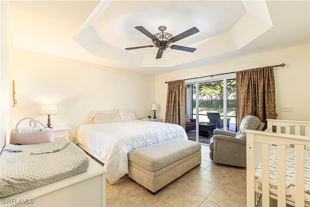 tiled bedroom with ceiling fan, access to outside, and a tray ceiling